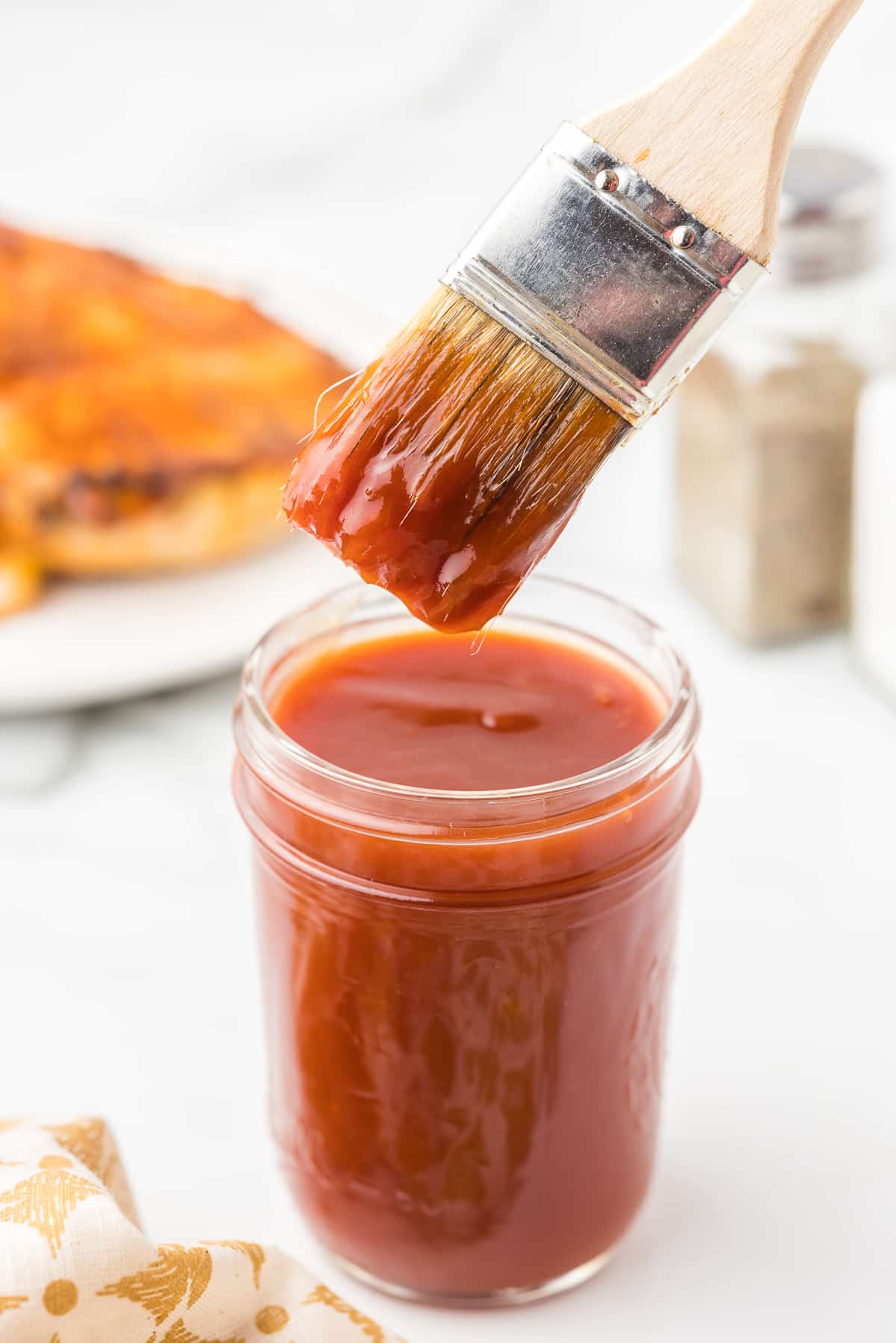 A brush inside of a jar ob apricot bbq sauce.
