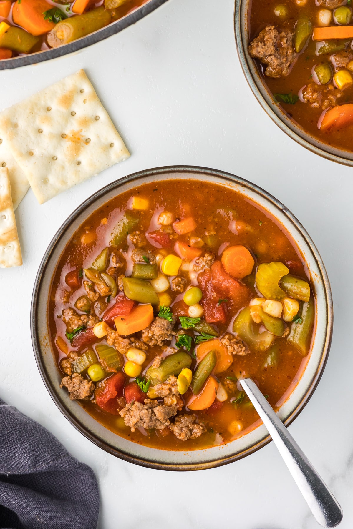 Hearty hamburger soup in a bowl with crackers.