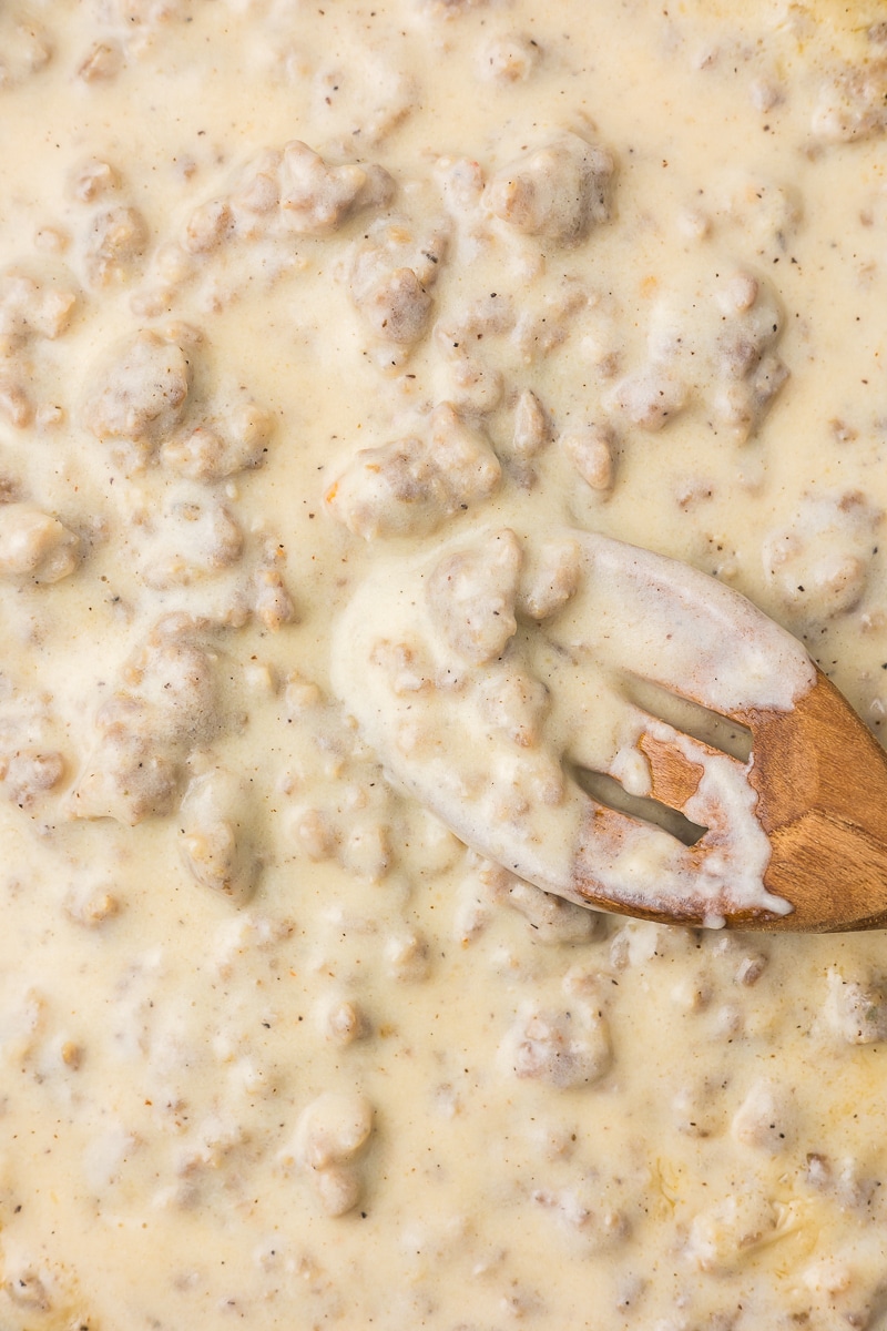 Sausage gravy with a wooden spoon.