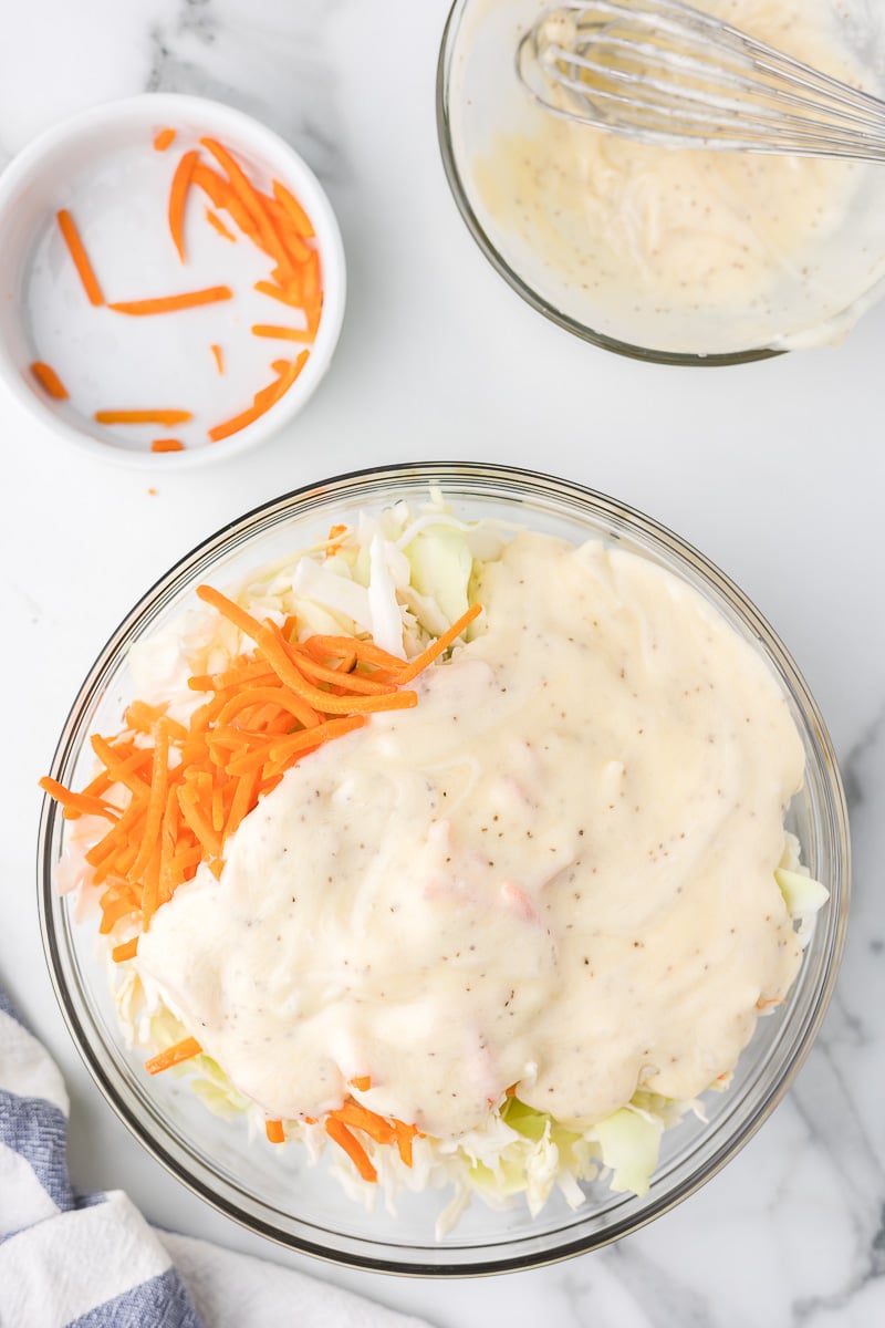 Coleslaw and carrots with dressing before mixing.
