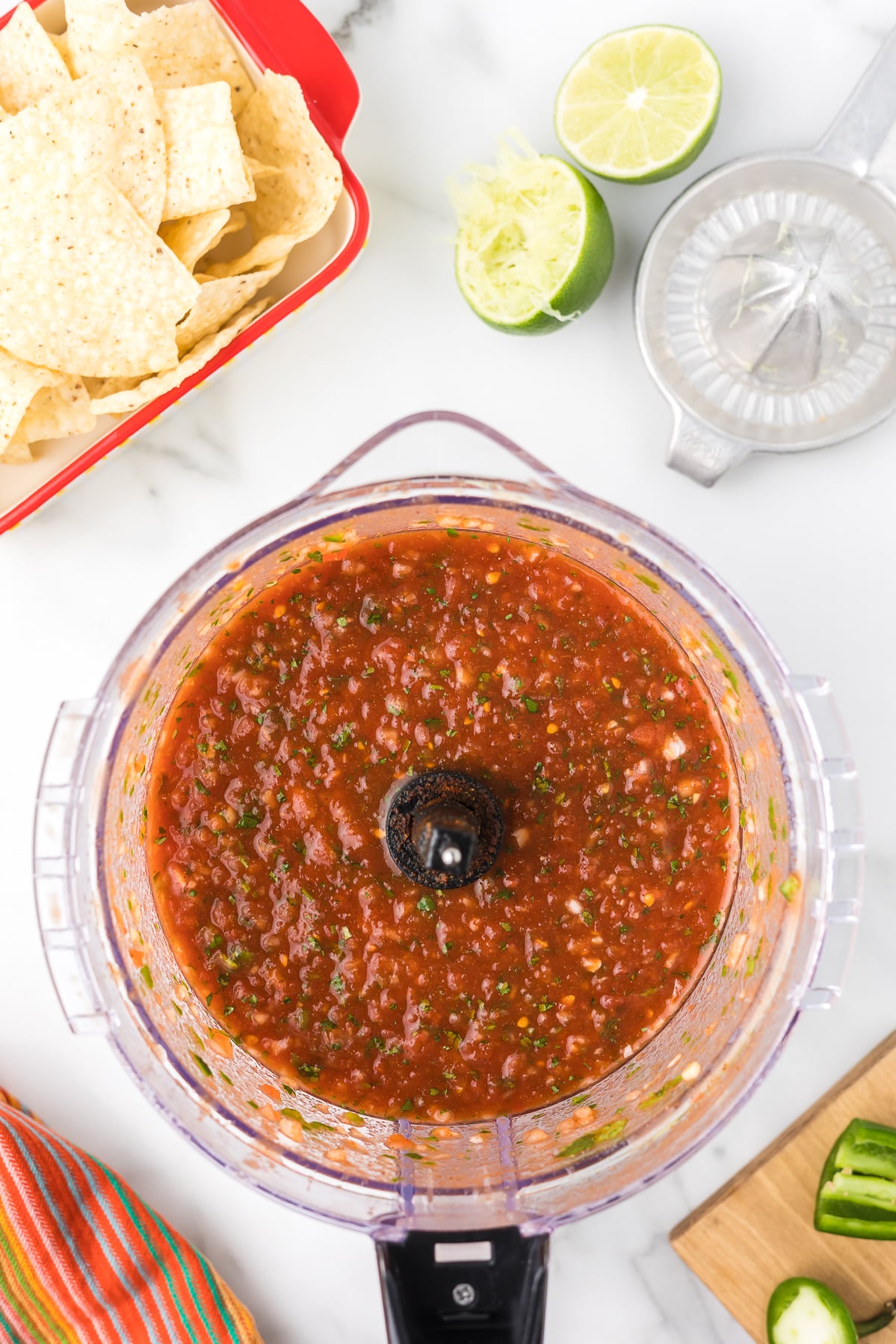 Blended salsa in a food processor bowl before serving with chips.