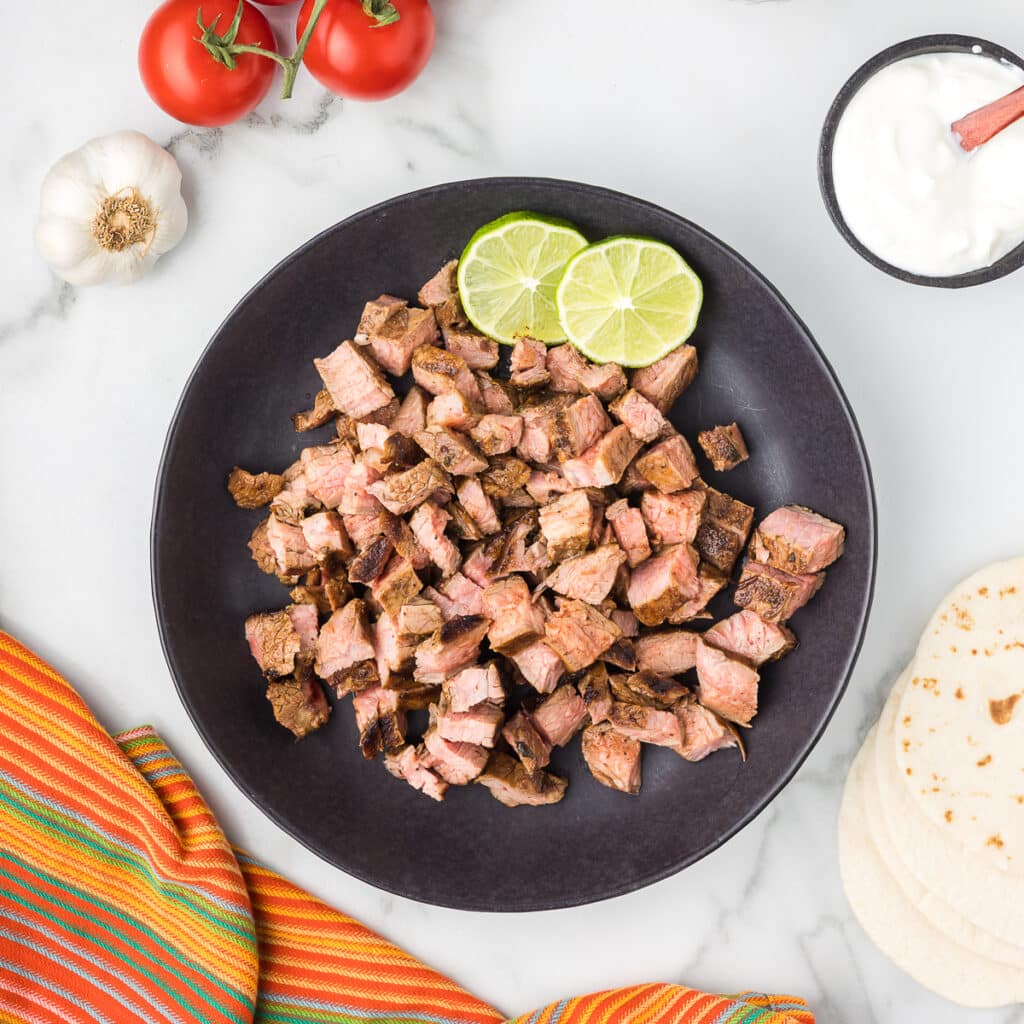 Chipotle Carna Asada in a black bowl with limes.