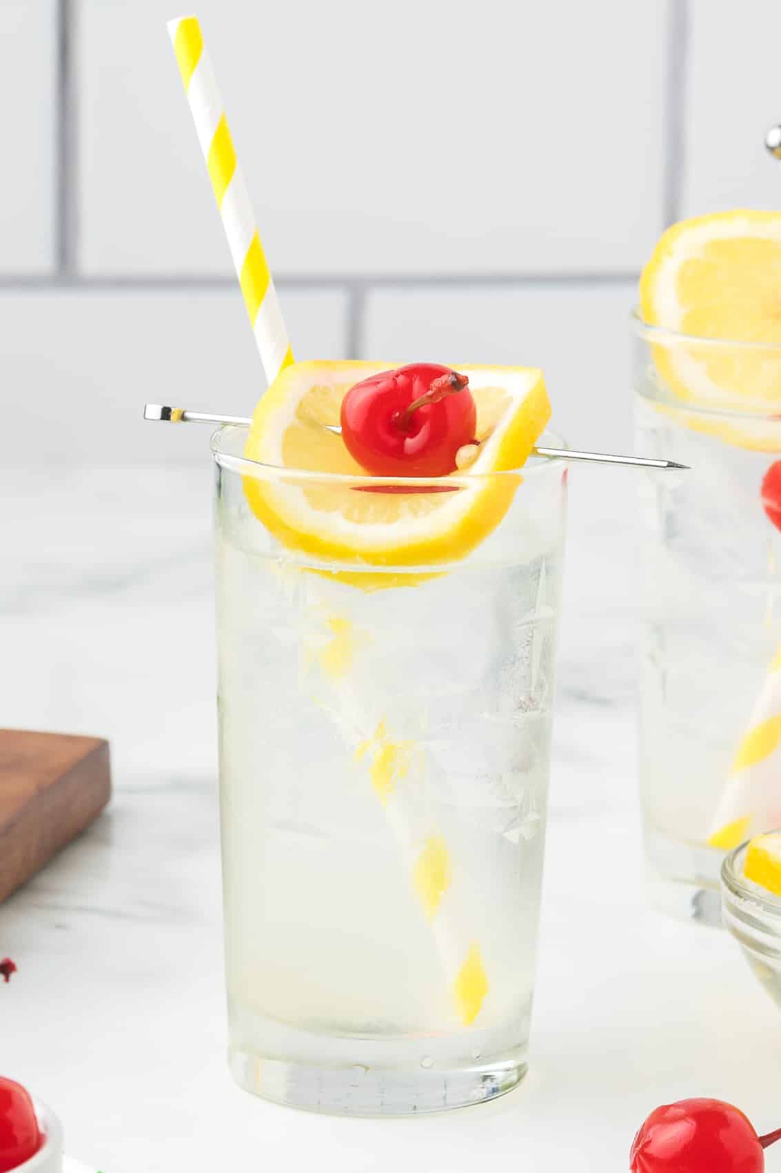 Rum Collins with a straw, lemon slice and cherry.