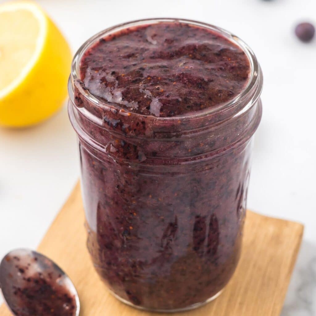 Blueberry Puree in a mason jar on a cutting board.