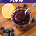 Homemade blueberry puree in a jar with a spoon.