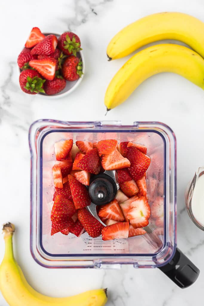 Frozen bananas and fresh strawberries in a blender.