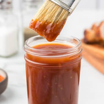 Honey bourbon bbq sauce in a jar with a bbq brush.