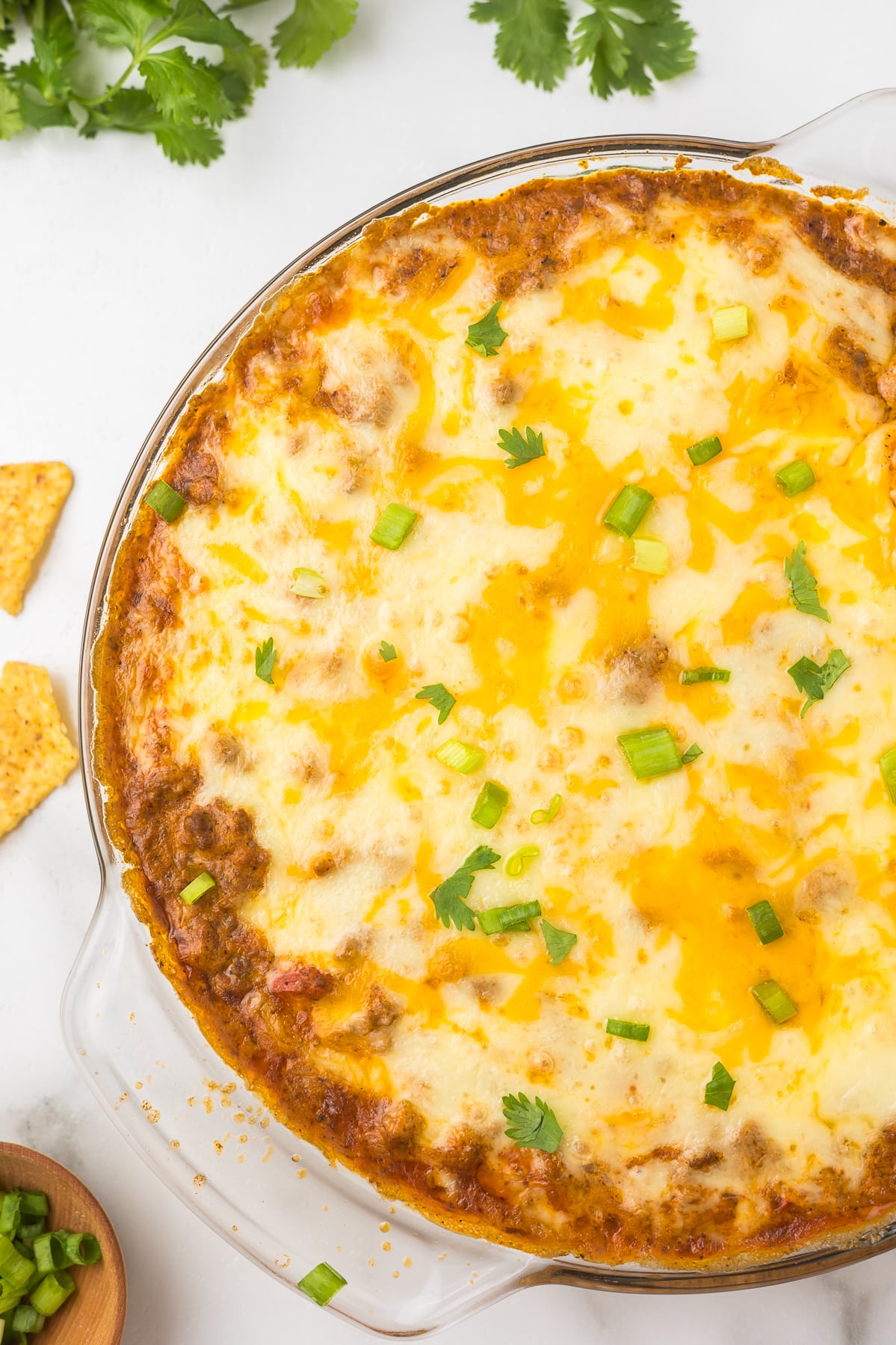 A clear pie pan with hot taco dip.