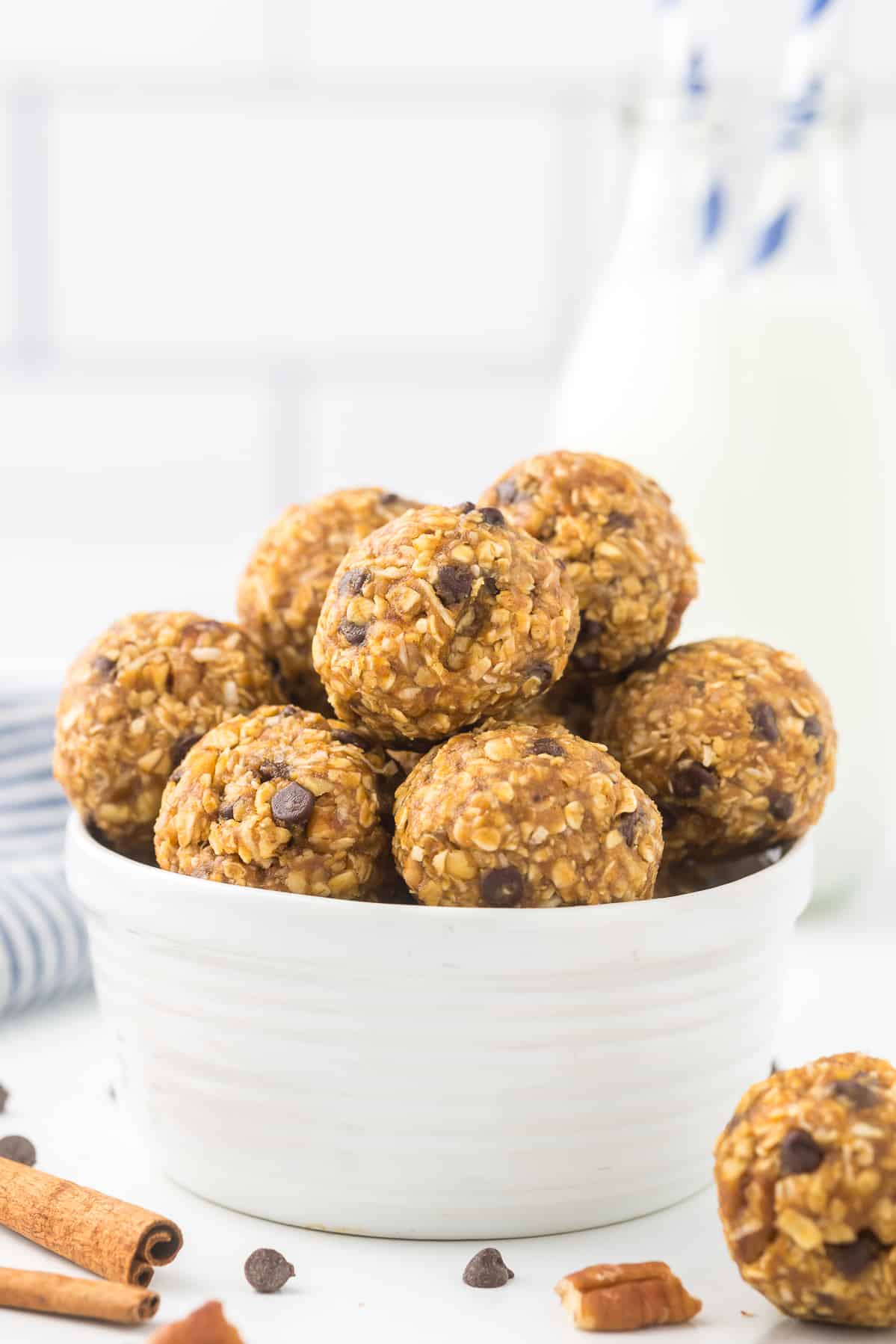 Pumpkin Protein Balls in a white bowl with milk in the background.