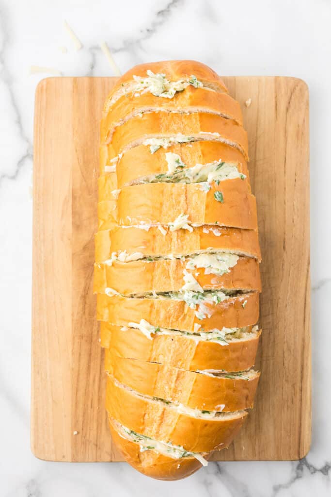 A loaf of bread sliced and stuffed with a garlic butter and cheese.