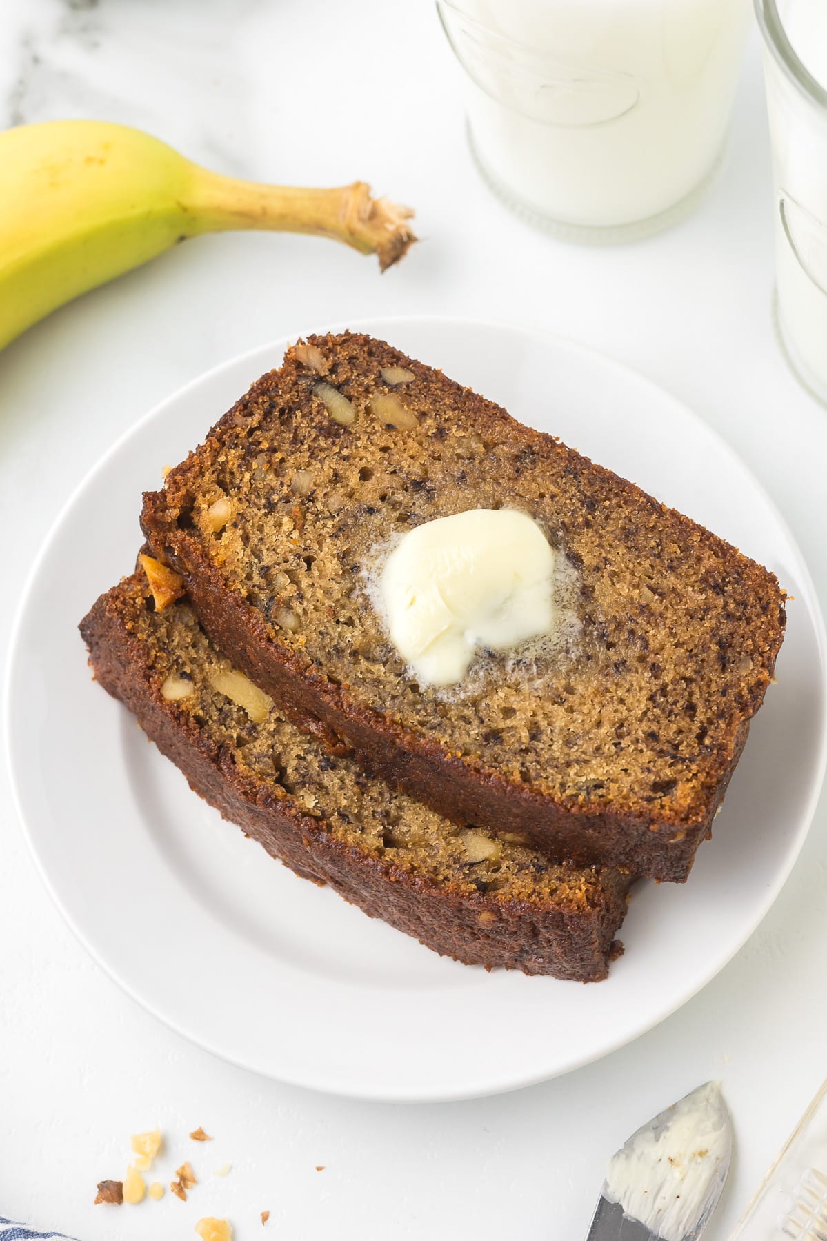 Two slices of banana bread with a pat of butter.