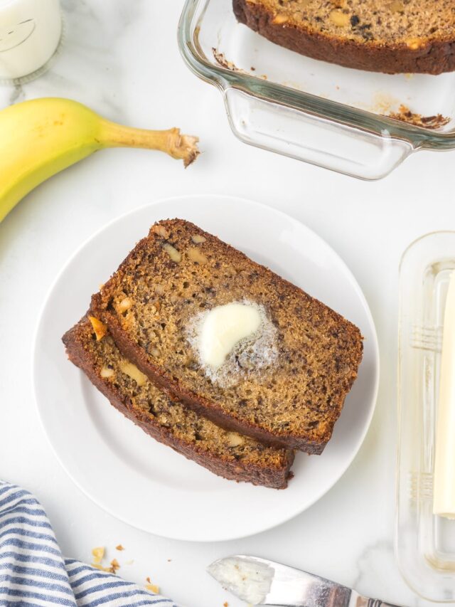 Banana Bread on a white plate with more bread and a banana around the plate.