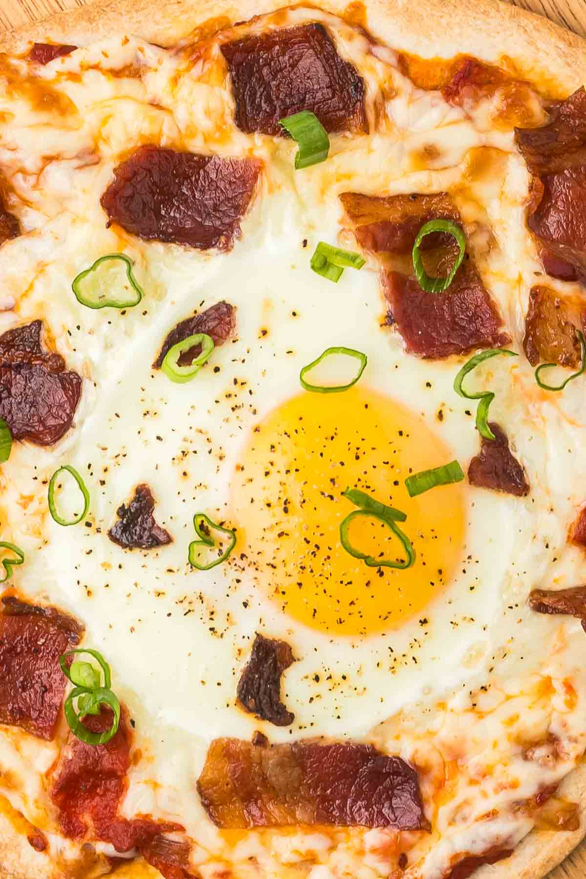 Tortilla Breakfast Pizza on a cutting board with green onions as garnish.