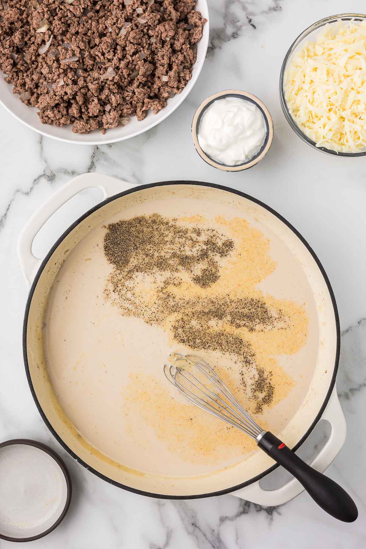 Cream sauce with a whisk and spices added.