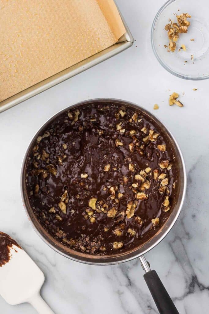 Sauce pan with brownie ingredients including walnuts mixed in.