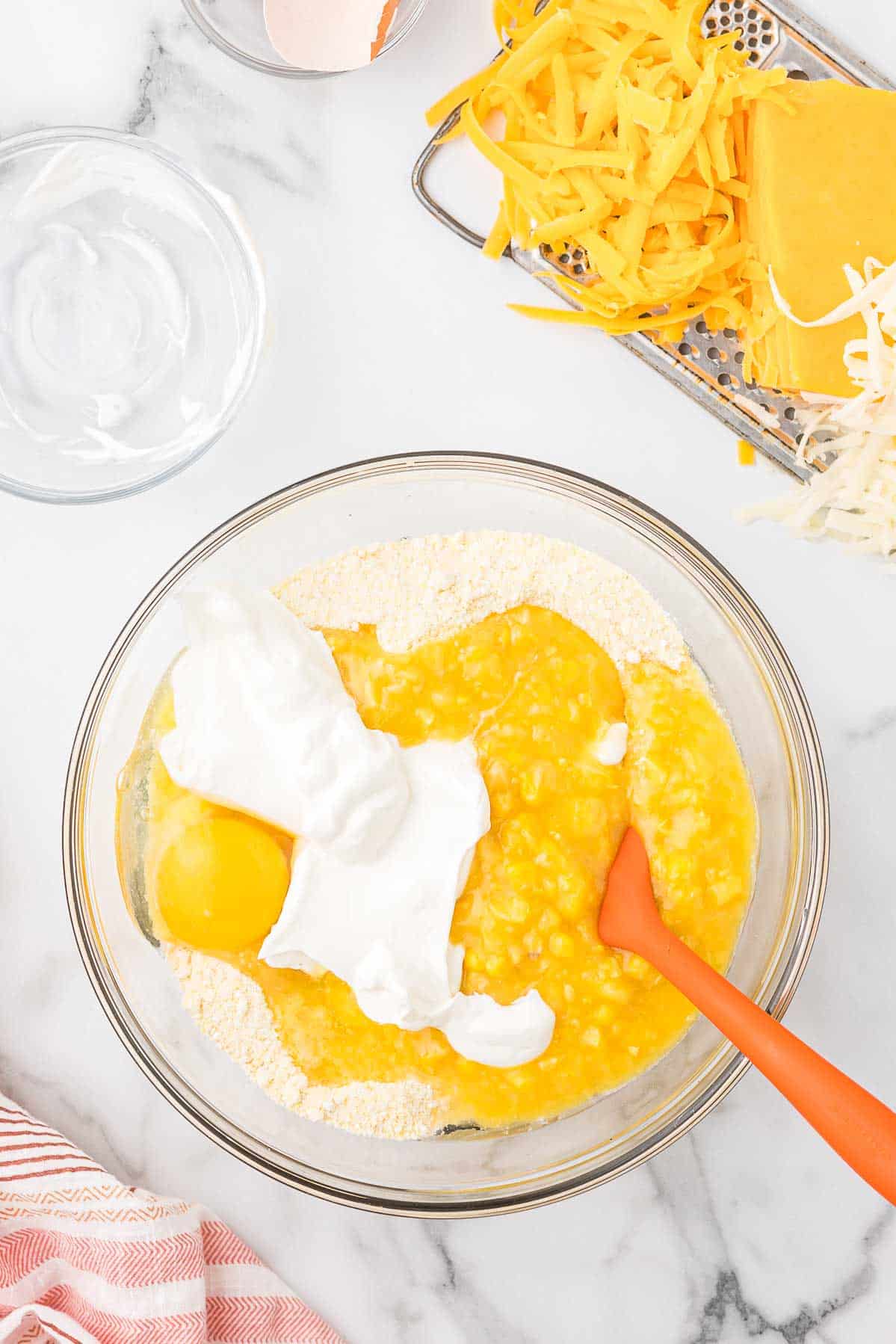 Cornbread ingredients in a mixing bowl including Jiffy cornbread, egg, cream corn and sour cream.