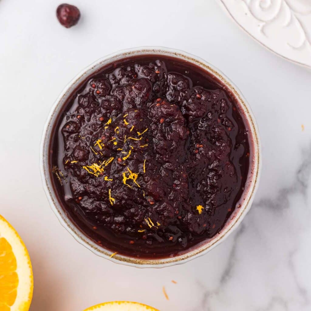 Craisins Cranberry sauce in a bowl with oranges near.