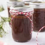 Hot fudge sauce in a mason jar with a red and white ribbon for gift giving.