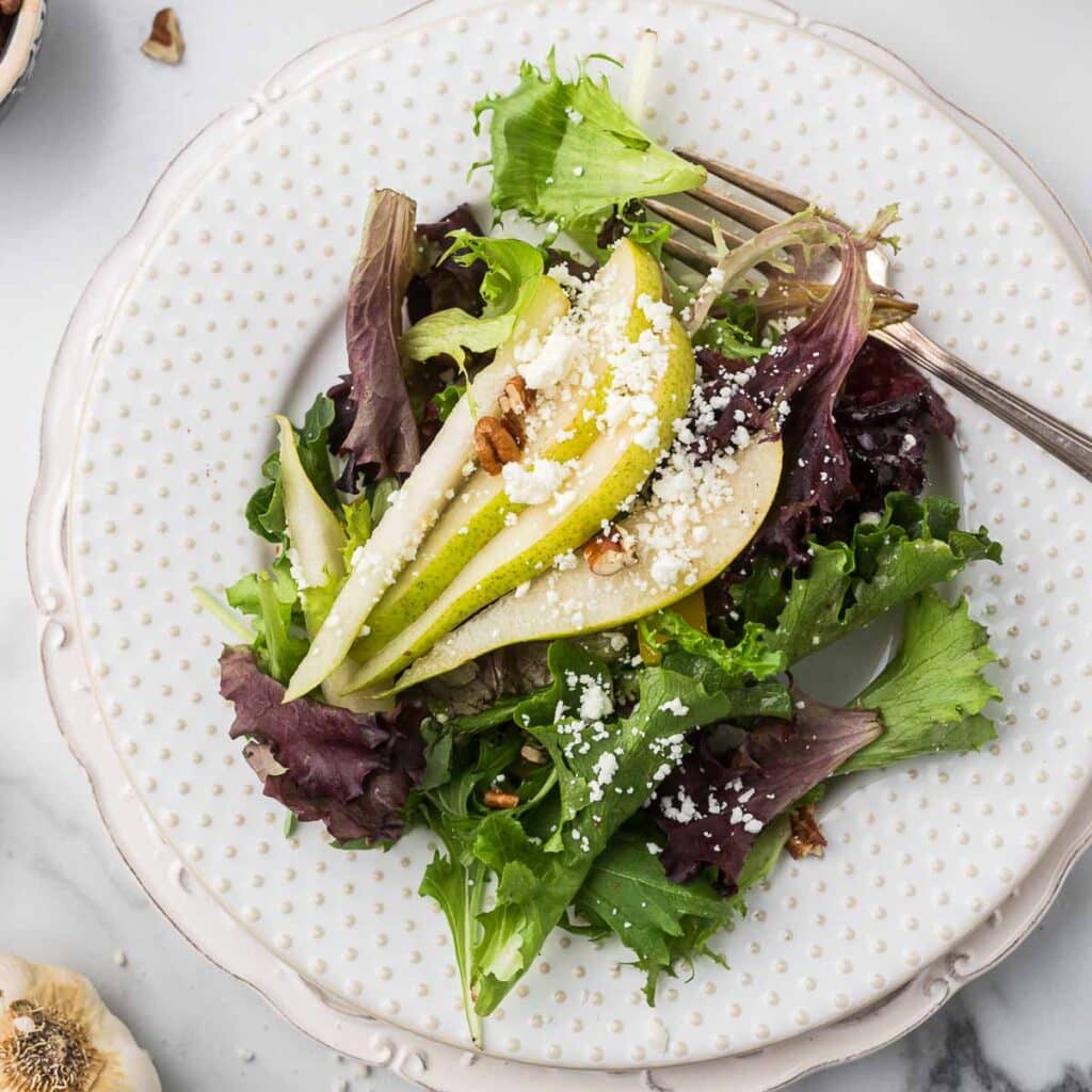 Pear and Pecan Salad on a white plate with a fork.