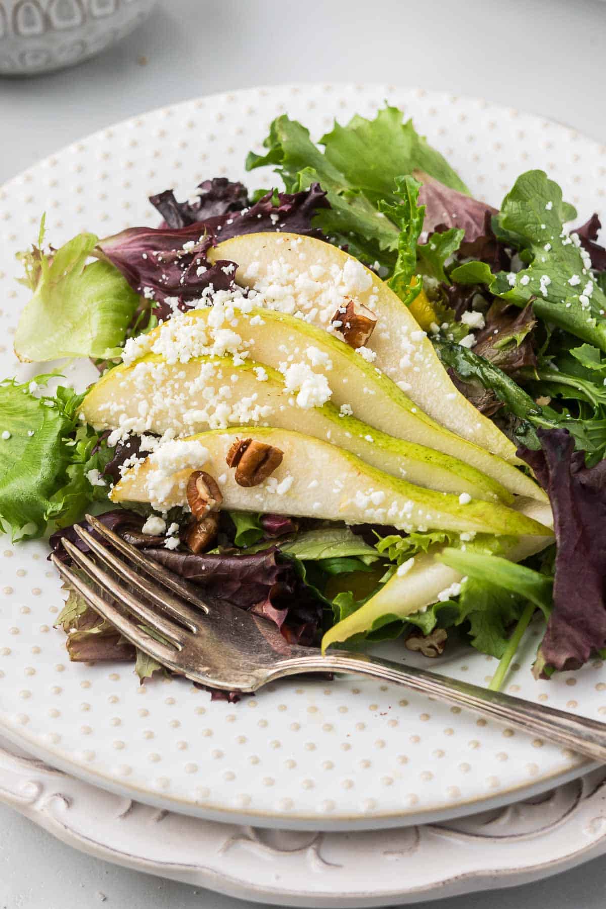 A small plate of pecan and pear salad.