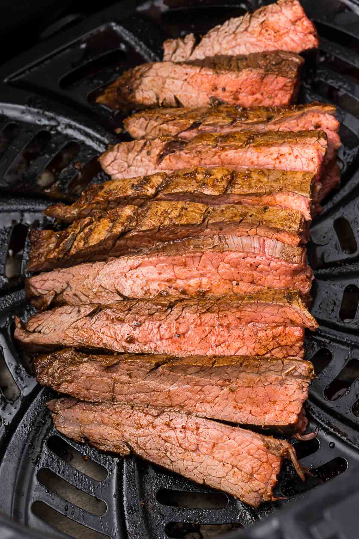 Flank steak in an air fryer basket after it has cooked.