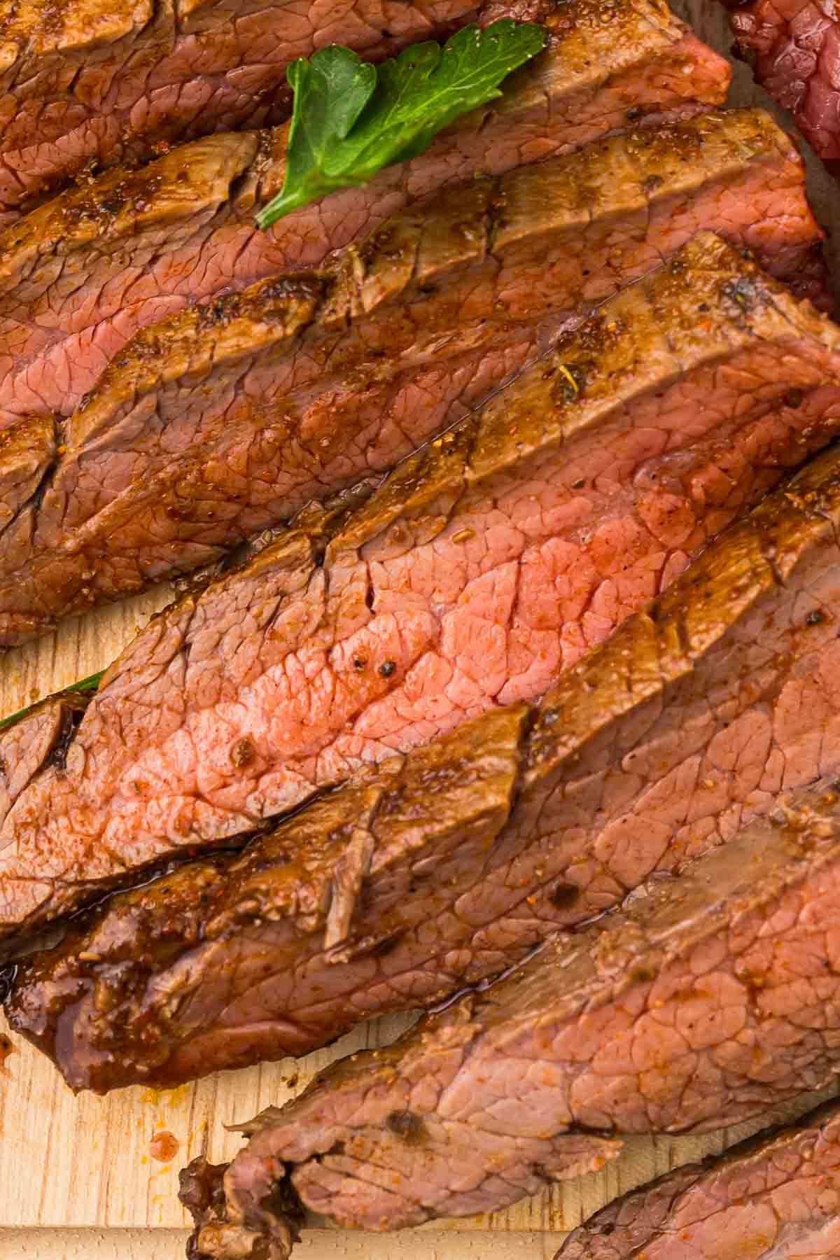 Sliced air fryer flank steak on a wooden cutting board.