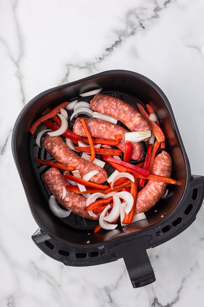 Air Fryer Italian Sausage with onions and red bell peppers added to the basket.