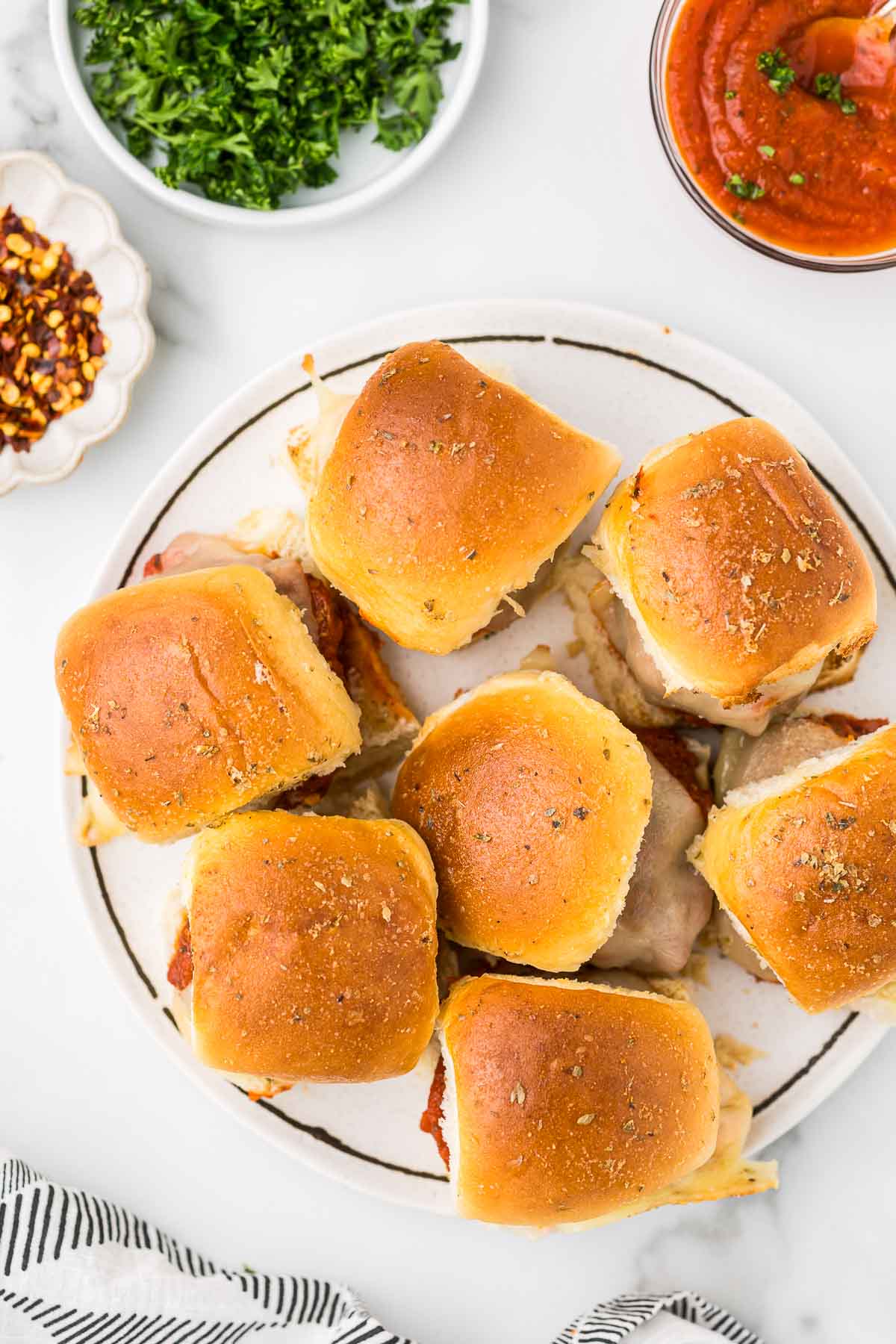 Seven meatball sliders on a plate.