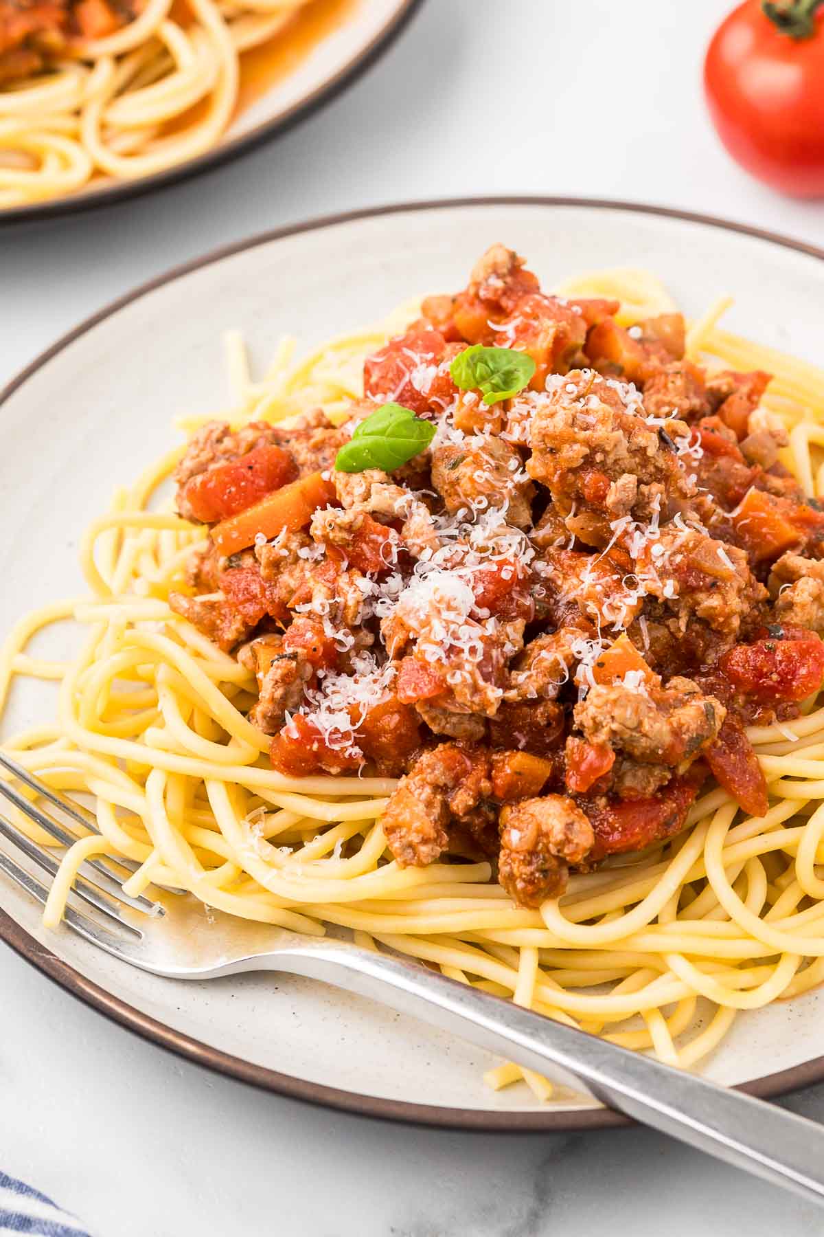 A plate of chicken bolognese sauce on a bed of spaghetti. 
