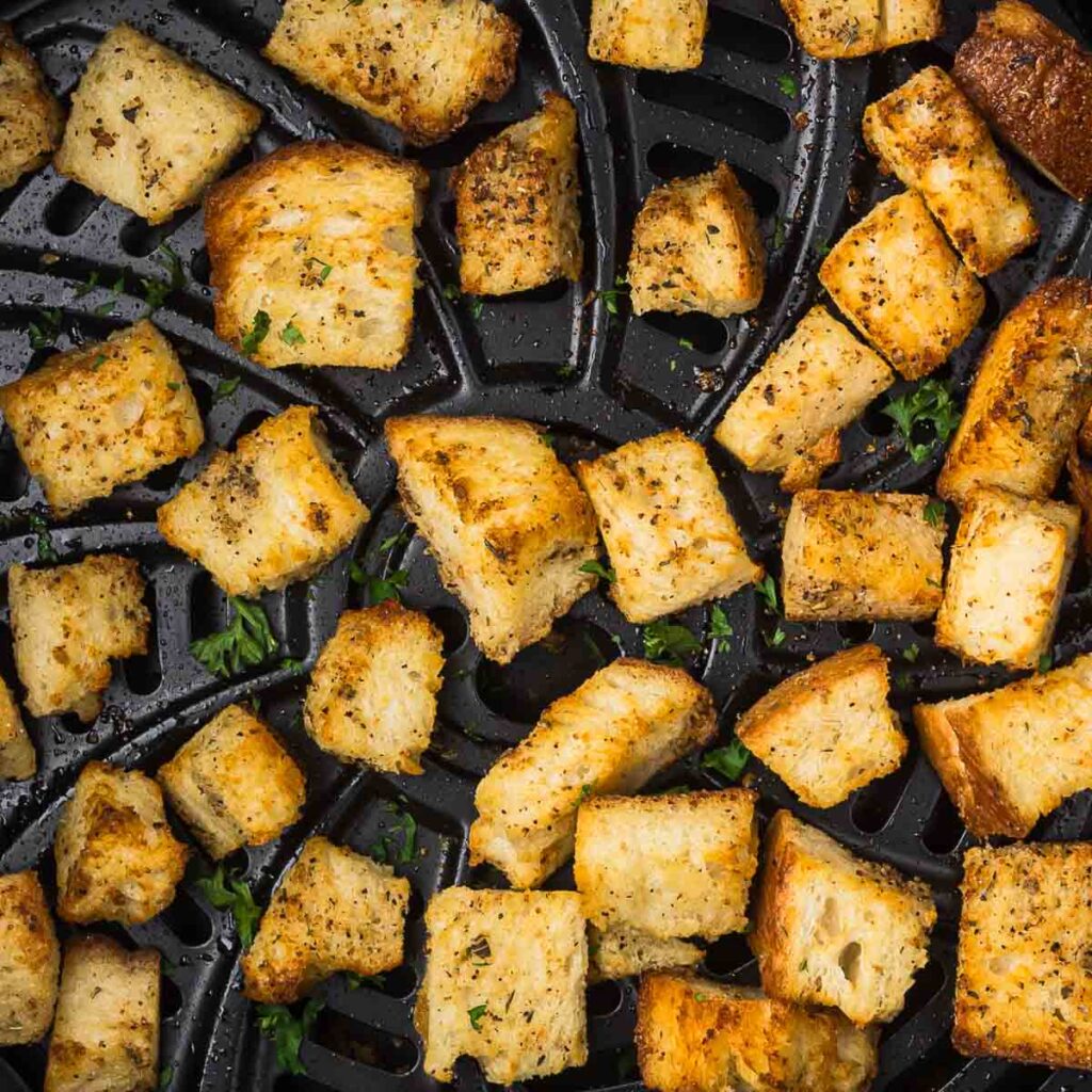 Croutons in an air fryer basket.