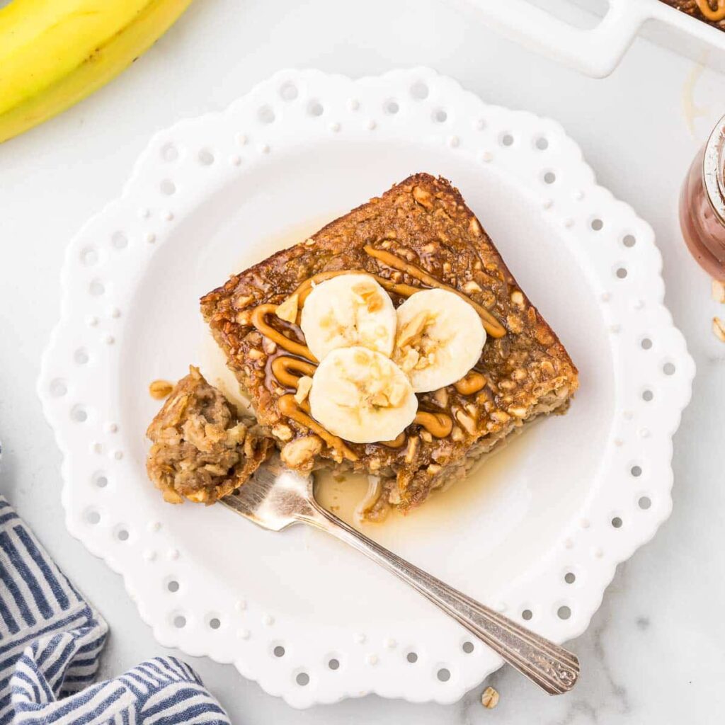 Baked Oatmeal on a plate with banana slices and a few peanuts on top.