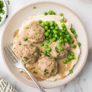 Swedish Meatballs served over mashed potatoes with green peas.