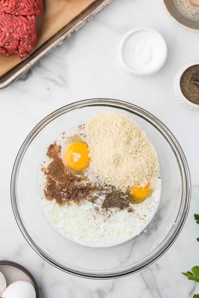 Ingredients to make meatballs in a bowl before mixing.