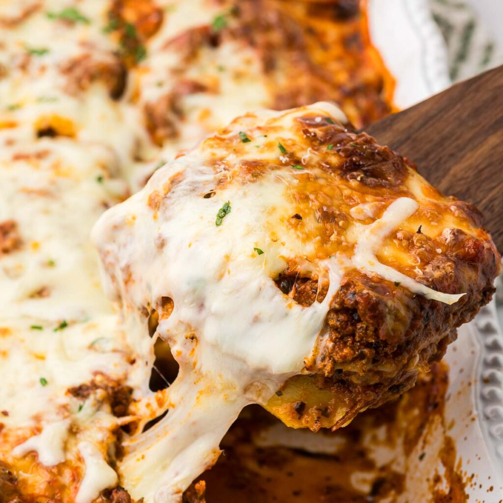 Baked Ravioli in a casserole dish with a wooden spatula.