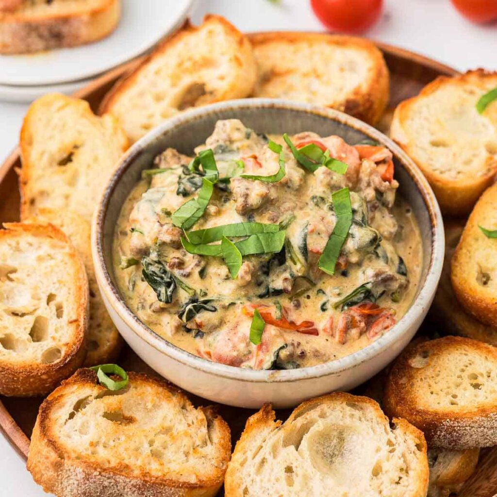 Boursin cheese dip in a bowl with basil and bread.