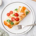 Pulled Pork Burrito with cilantro and tomatoes on a white plate with a fork.