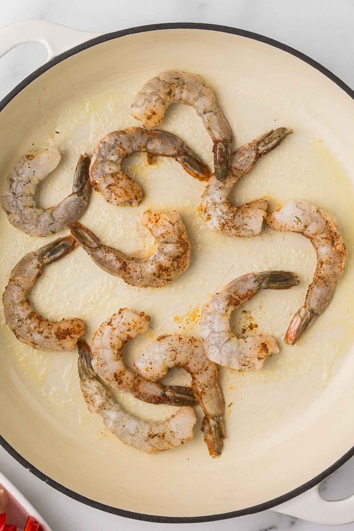 Shrimp in a pan with oil and cajun seasoning.