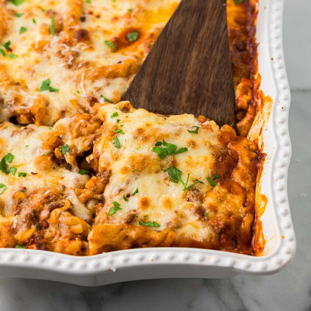 Lasagna Casserole in a white baking dish with a spatula serving one piece.