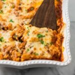 Lasagna Casserole in a white baking dish with a spatula serving one piece.
