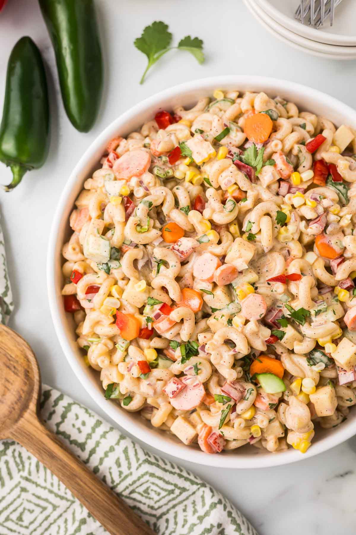 Mexican Macaroni Salad in a white bowl with a linen and some jalapenos.