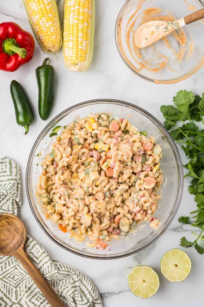 Macaroni salad with the sauce in a mixing bowl.