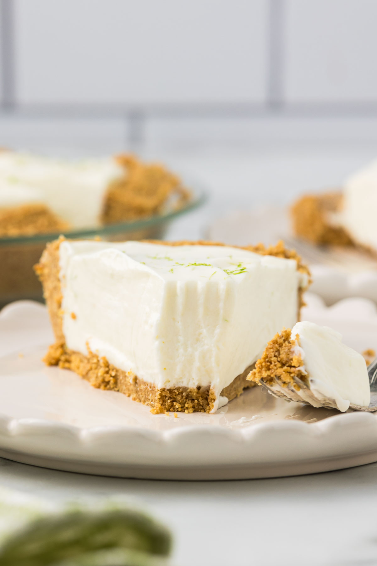 Key Lime pie on a plate with one bite on a fork.