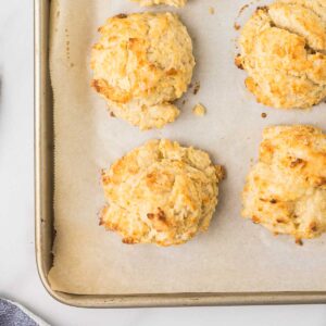 Buttermilk Drop Biscuits on a cookie sheet that is lined with parchment paper.