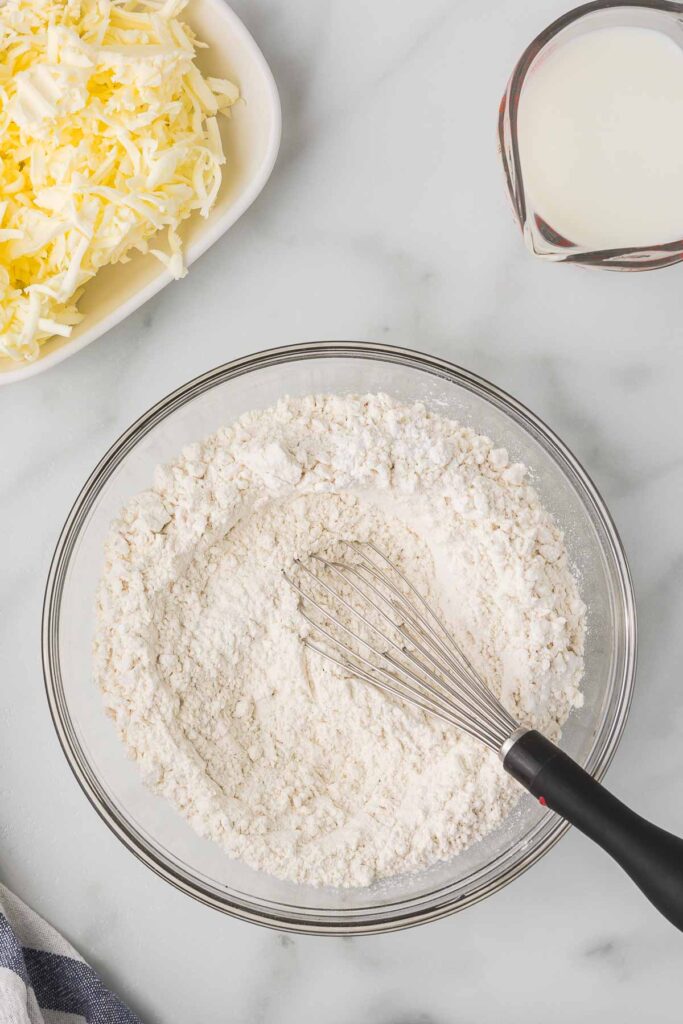 Grated butter, butter milk and flour in a bowl with a whisk