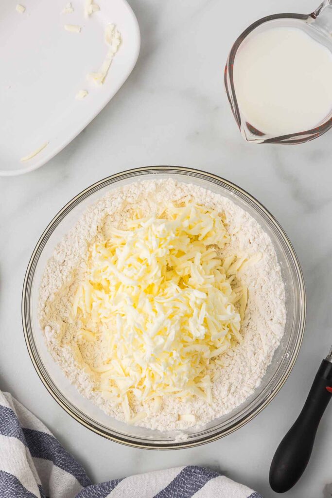 Flour with the grated butter in a bowl, buttermilk in a measuring cup.