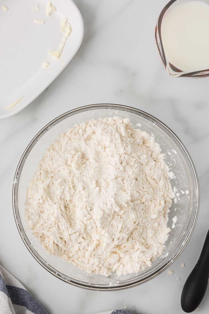 Flour and butter combined in a bowl, buttermilk in a measuring cup.