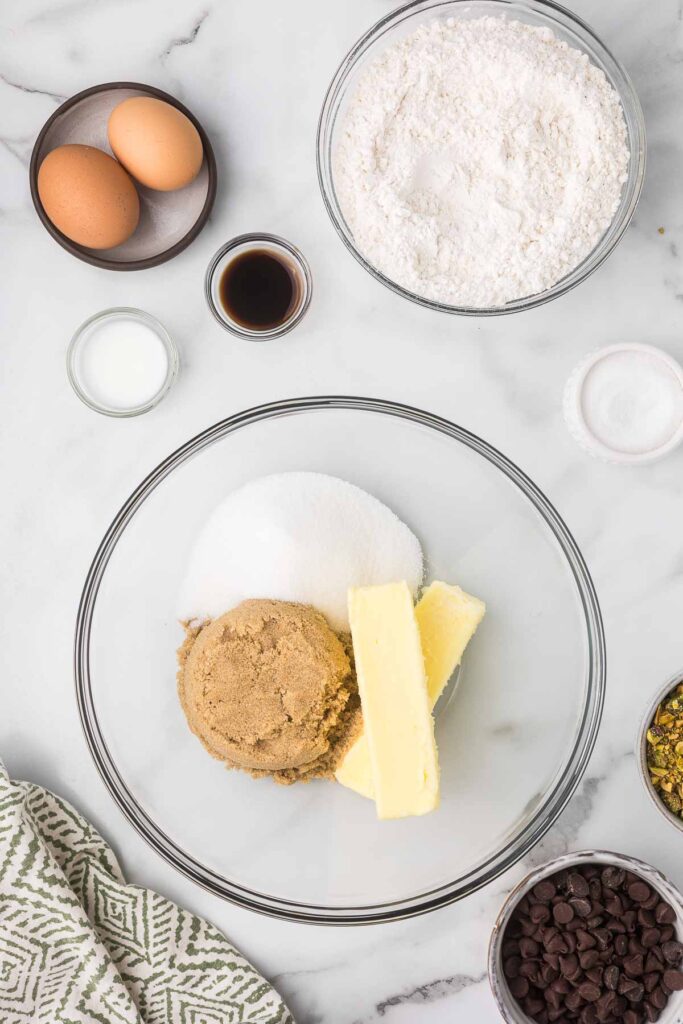 A bowl with brown sugar, granulated sugar and butter in a clear bowl.