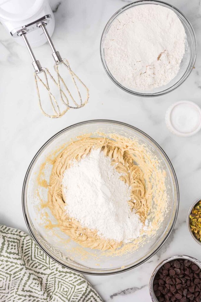 Flour being mixed into cookie dough to make chocolate chip pistachio cookies.