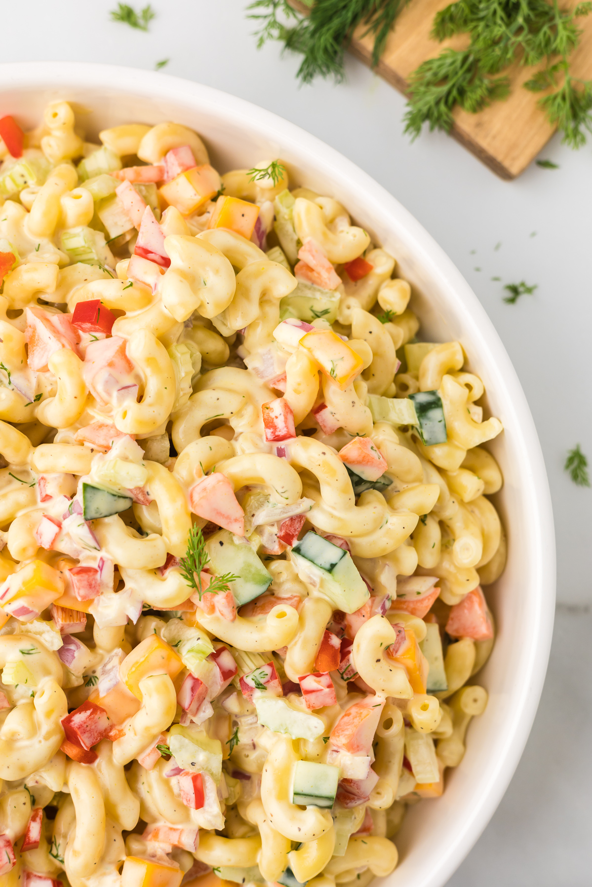 Creamy macaroni salad in a white bowl.