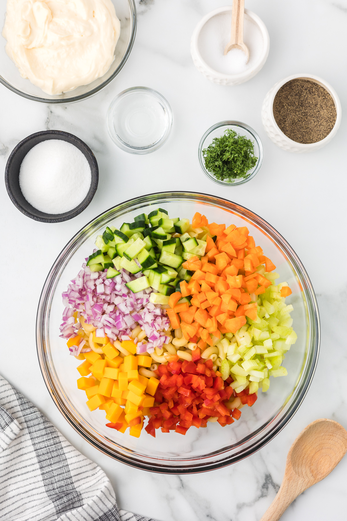 Vegetables in a clear bowl to make macaroni salad.